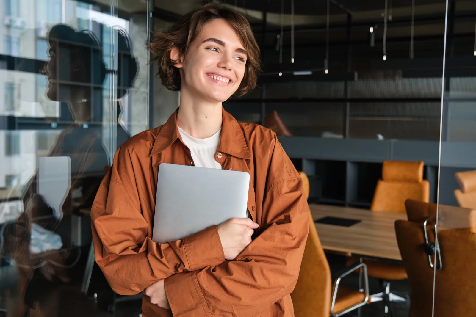 Confident professional woman with laptop smiling in office